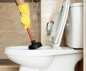 En hånd som tar en avløpsåpner i do